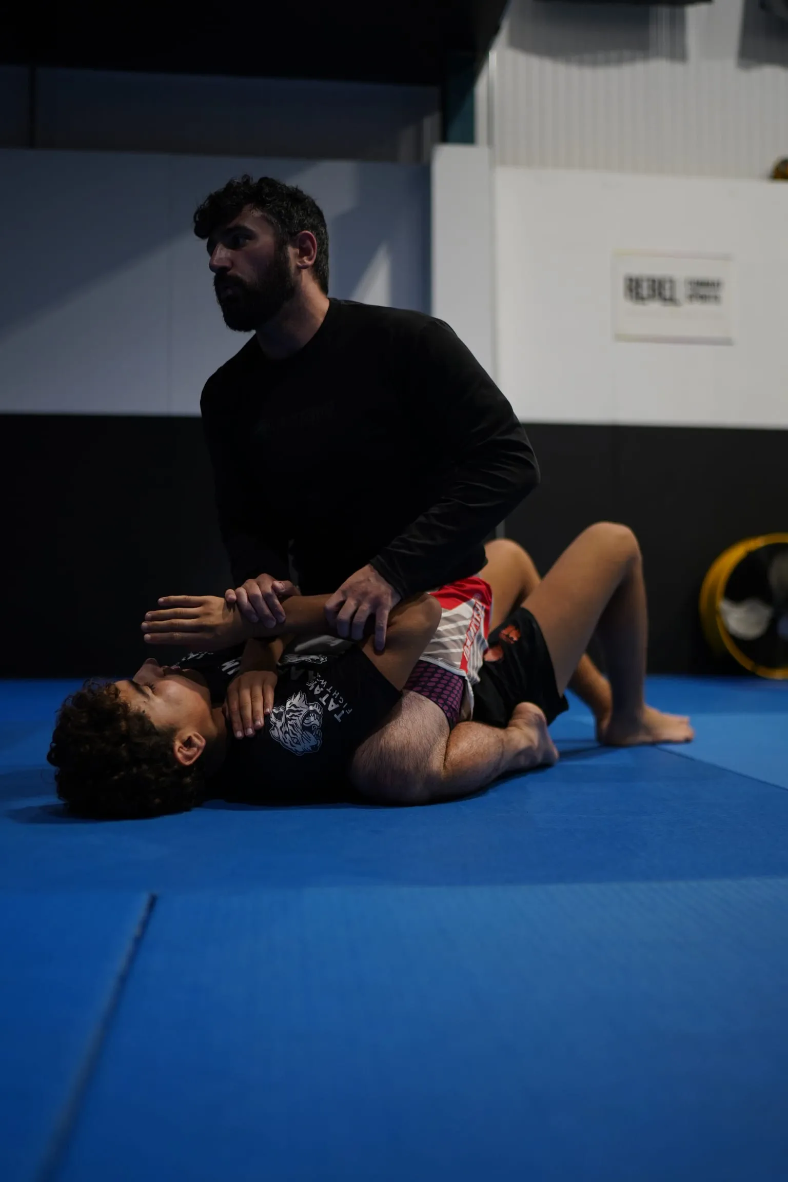 A grappler holding top position and pinning a training partner’s arm during a no-gi class at Rebel Combat Sports