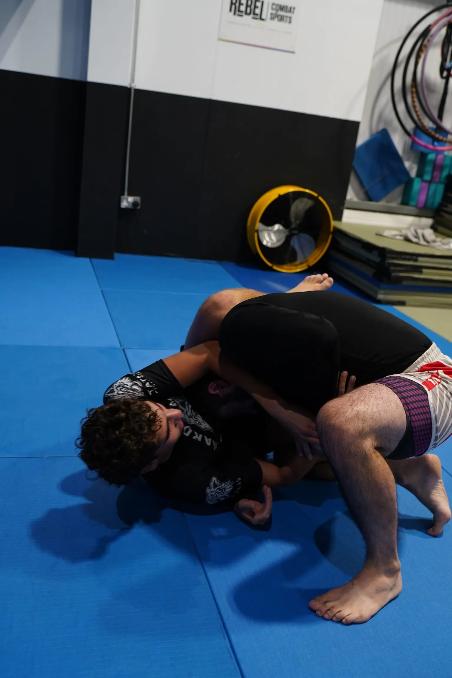 A grappler on top of a turtled training partner during a no-gi class at Rebel Combat Sports