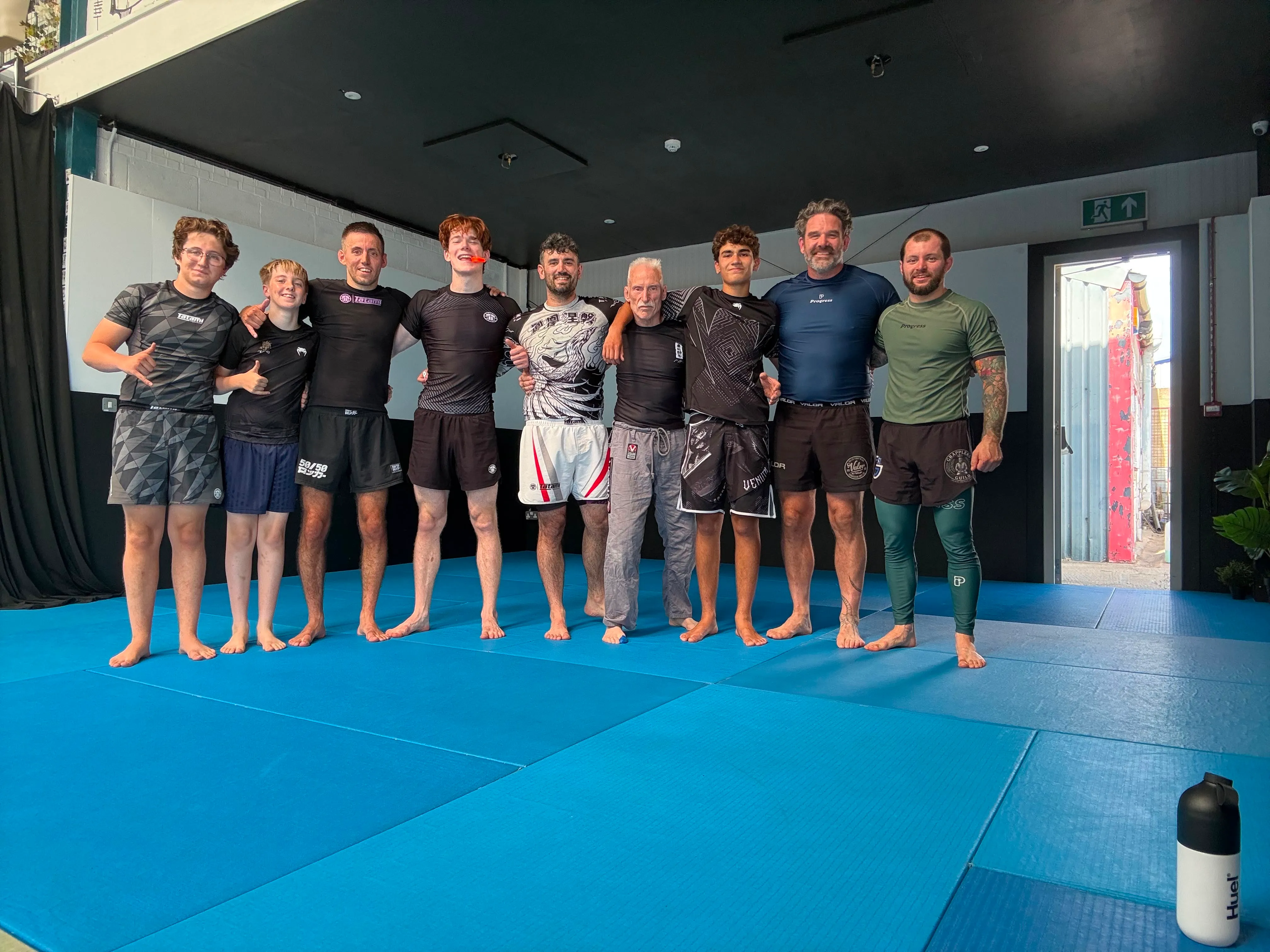 Nine Rebel members lined up on the mats after a no-gi session in launch week