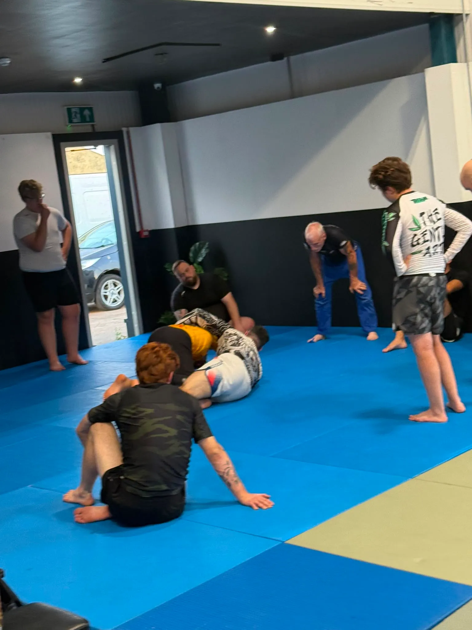 A live round at Rebel Combat Sports with other members watching from the edge of the mats